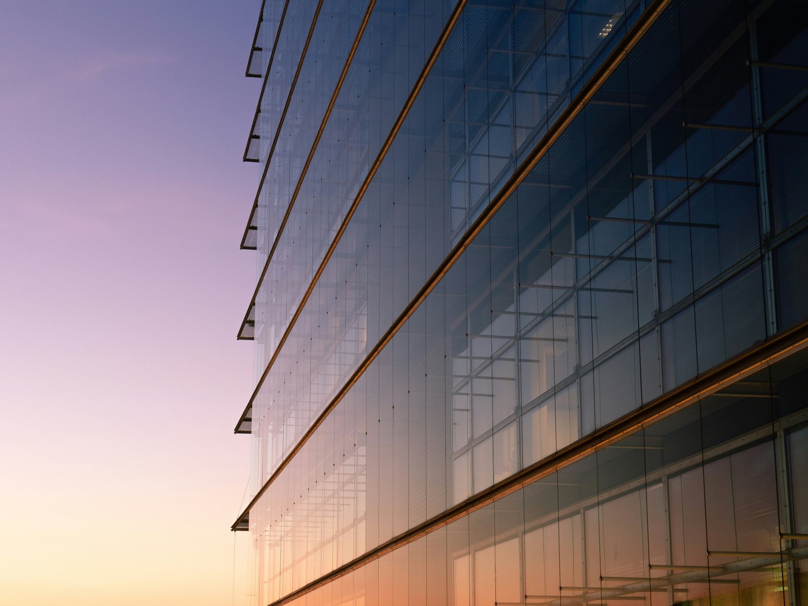 Glass office building facade at sunset